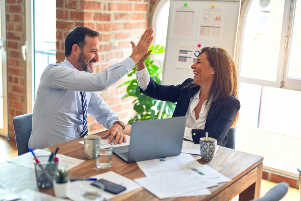 Two people shaking hands over a desk, illustrating the agency agreement behind ad account ownership