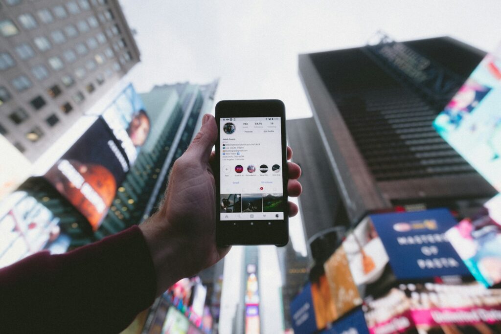 Phone showing a real estate brand's Instagram profile against city buildings